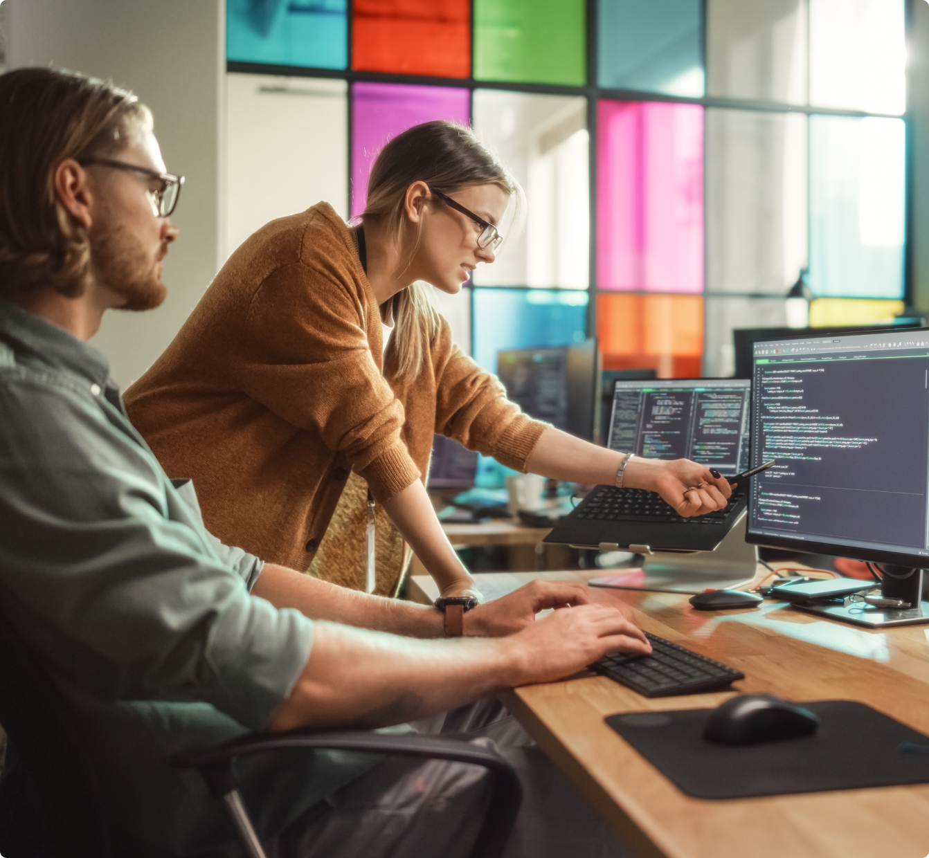 Two people reviewing data on several monitors