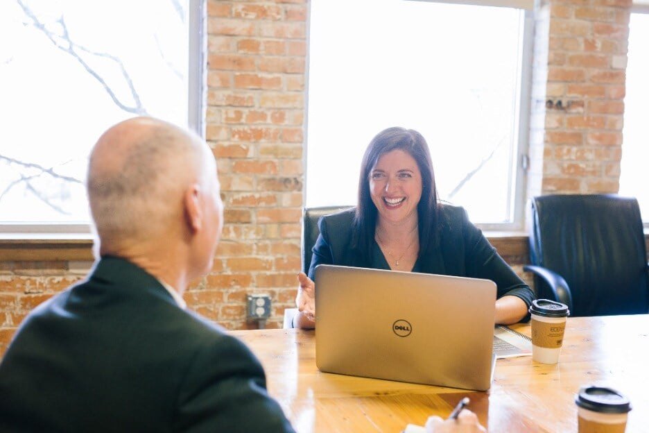 smiling woman looking at man over her laptop